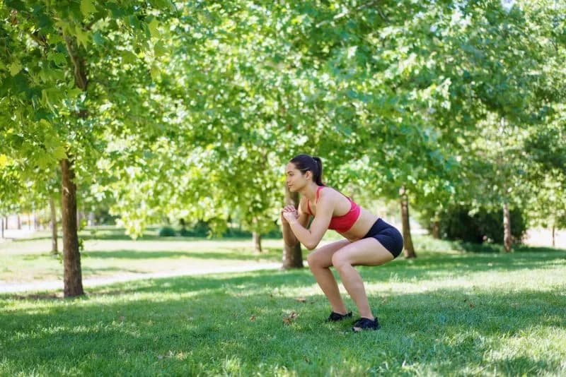 a woman is doing squats in a green park 2026 03 24 21 49 37 utc
