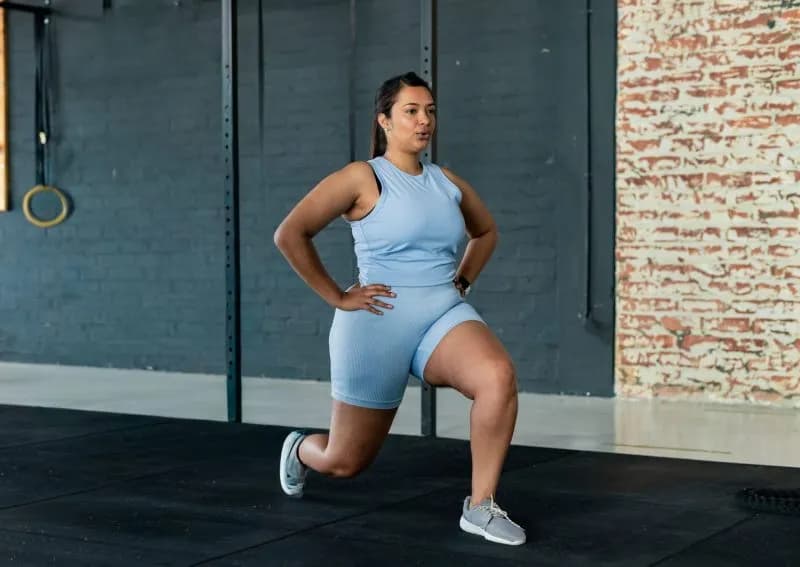 asian woman performing lunge in gym