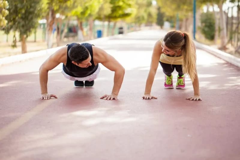 athletic man and woman doing pushups outdoors