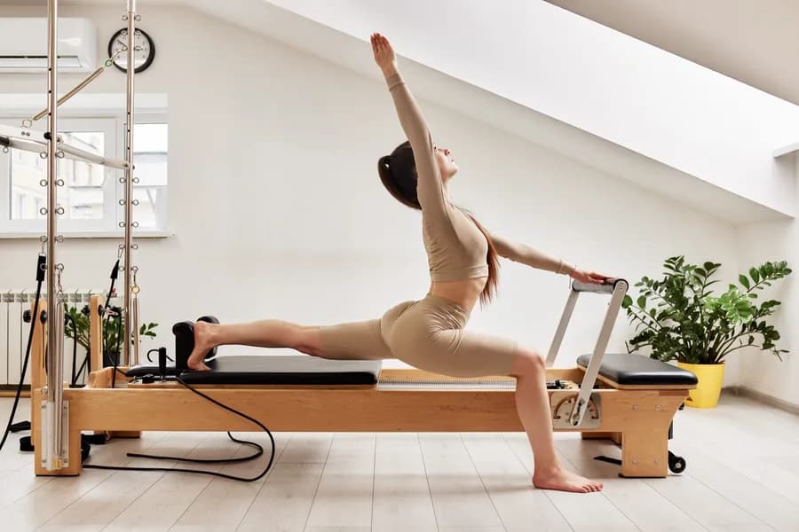 Young woman doing pilates on a reformer bed