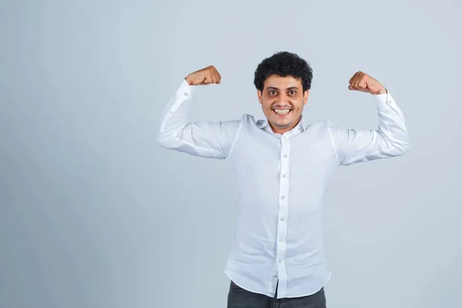 Young man showing muscular arms in a white shirt, looking powerful