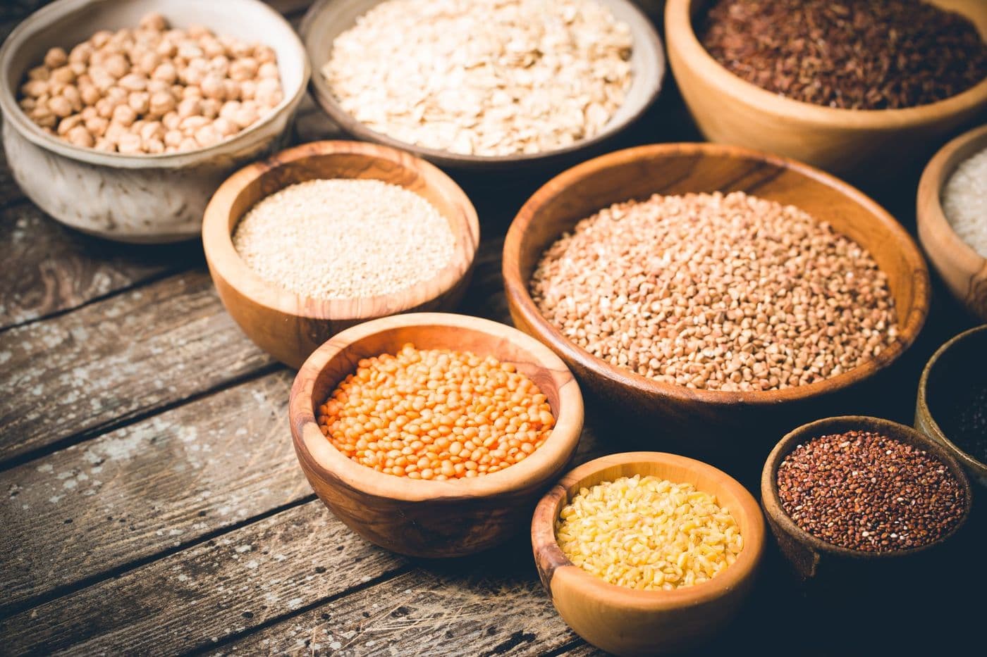 Assorted dried grains and legumes soaking in wooden bowls
