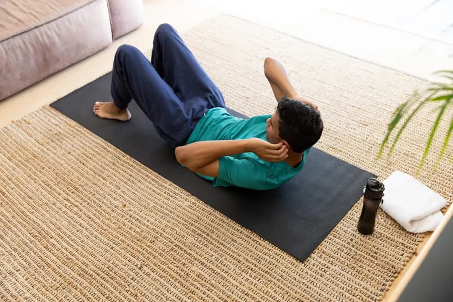 Man doing crunches at home on a yoga mat