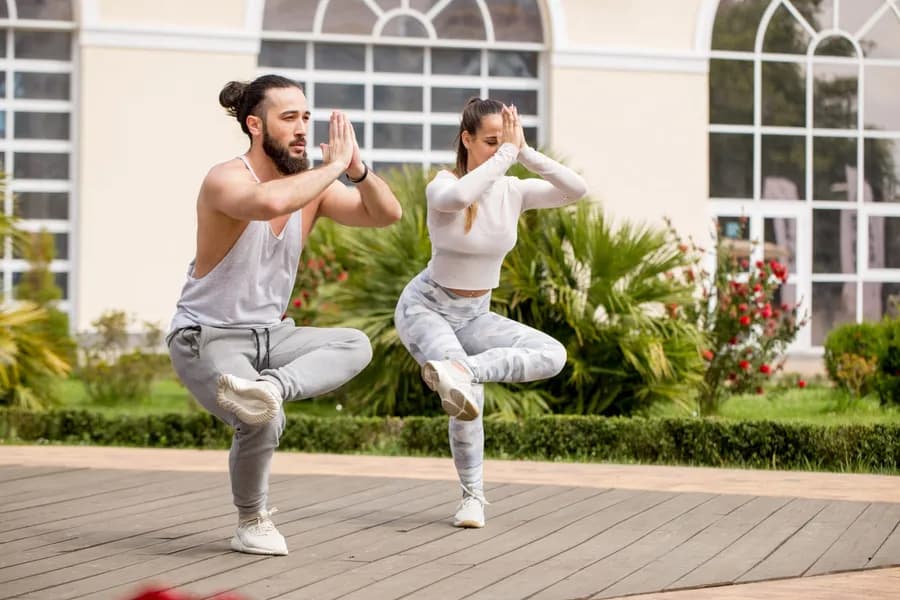 Man and woman practicing yoga in park
