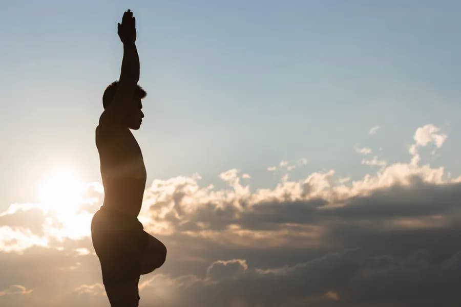 Man practicing yoga asana at sunset