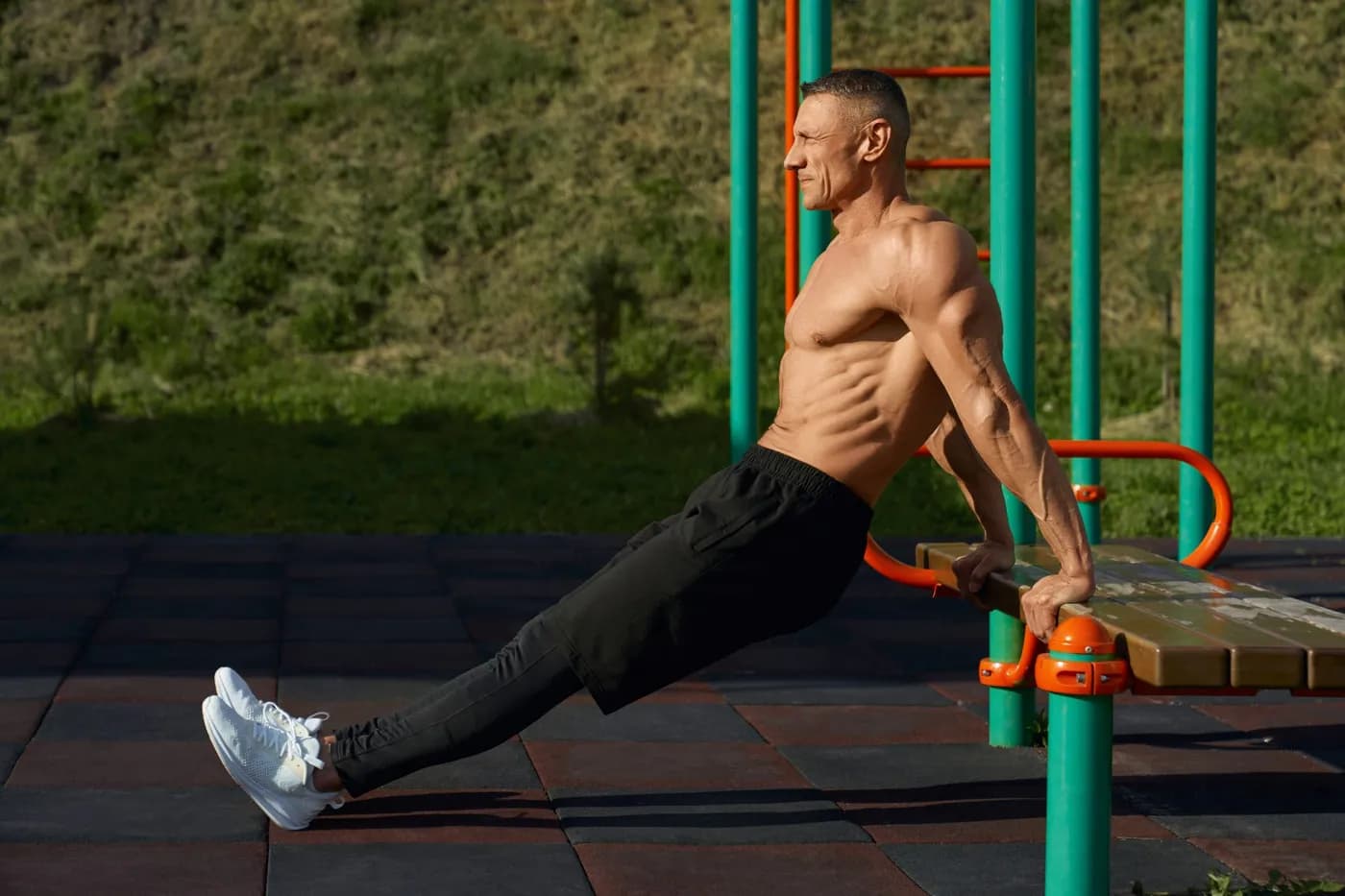Athletic man doing tricep dips in an urban park