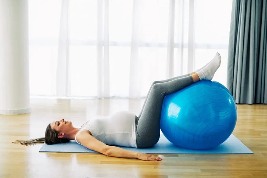 Woman exercising with an exercise ball on a yoga mat — Habuild