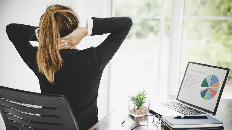 Young woman experiencing neck pain while sitting at her desk during work