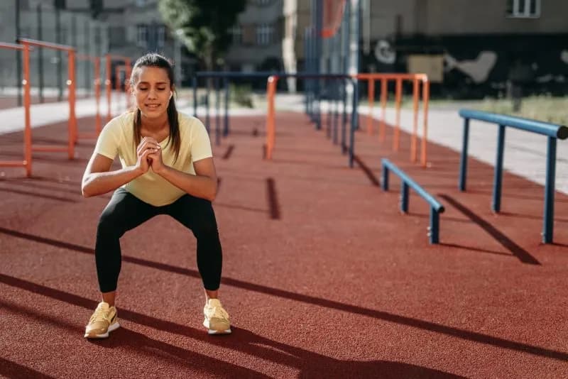 woman doing squats outdoors on a sunny day