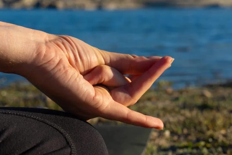woman s hand doing a mudra in nature with a lake b 2026 01 06 10 52 54 utc